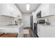 Modern kitchen featuring white cabinets, stainless steel appliances, and gray wood-look flooring at 3907 W Walnut St, Tampa, FL 33607