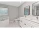 Bright bathroom featuring double sink vanity, soaking tub, and tiled floors at 4317 S Hale Ave, Tampa, FL 33611