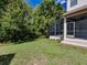 View of backyard, showing screen patio, green grass and some mature trees and plantings at 5224 Fairway One Dr, Valrico, FL 33596