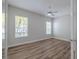 Bright bedroom features wood-look flooring, ceiling fan, and natural light from two windows at 5224 Fairway One Dr, Valrico, FL 33596