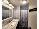 Bathroom with a single sink vanity, decorative mirror, and shower with floral curtain at 5258 Wisteria Cir, New Port Richey, FL 34653