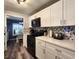 Spacious kitchen featuring white cabinets, updated appliances, and unique backsplash with access to dining room at 5258 Wisteria Cir, New Port Richey, FL 34653