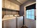 Functional laundry room with washer, dryer, overhead cabinets, and exterior access to the home at 5258 Wisteria Cir, New Port Richey, FL 34653
