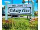 Charming welcome sign to Colony Cove surrounded by bright red flowers, inviting visitors to a beautiful community at 5258 Wisteria Cir, New Port Richey, FL 34653