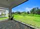 View from a covered patio, showcasing brick flooring and a serene backyard with lush greenery and a clear blue sky at 5336 Patano Loop, Palmetto, FL 34221
