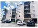 Exterior shot of building featuring multi-level screened balconies, palm tree and adjacent parking at 5541 Bay Blvd # 410, Port Richey, FL 34668