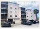 View of building exterior featuring screened balconies, white stucco and adjacent parking with a garage at 5541 Bay Blvd # 410, Port Richey, FL 34668