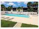 Community pool surrounded by a white fence and lounge chairs amid lush tropical landscaping at 5541 Bay Blvd # 410, Port Richey, FL 34668