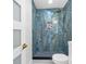 Updated bathroom showcasing a blue-tiled shower with gold fixtures, niche, and gray mosaic flooring at 5618 Halifax Dr, Tampa, FL 33615