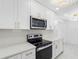 Close up of kitchen with stainless steel microwave and electric range, quartz countertops, and gold hardware at 5618 Halifax Dr, Tampa, FL 33615
