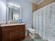 Bright bathroom features a granite vanity, toilet, and a seashell-themed shower curtain at 7427 20Th St, Zephyrhills, FL 33540