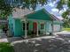 Charming home featuring a welcoming front porch, vibrant turquoise paint, and a red front door at 7427 20Th St, Zephyrhills, FL 33540