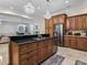 A kitchen island has a sink and stainless steel dishwasher, with dark countertops and light wood cabinets at 7427 20Th St, Zephyrhills, FL 33540