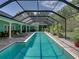 Stunning full view of a screened-in pool area with lounge chairs, lush plants and blue water at 7427 20Th St, Zephyrhills, FL 33540