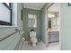 A clean bathroom with a toilet, mirror, and view into a second bathroom with a vanity, sink, and lighting at 8671 Cypress Lakes Blvd, New Port Richey, FL 34653