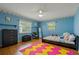 Bright, blue bedroom with a bed, a large pink and yellow rug, and two windows, offering a comfortable and inviting space at 8671 Cypress Lakes Blvd, New Port Richey, FL 34653