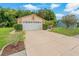 View of house exterior with 2-car garage framed by verdant shrubs and mature trees at 8671 Cypress Lakes Blvd, New Port Richey, FL 34653