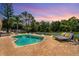 Backyard pool with a stone paver patio, chaise lounges, and tropical landscaping at dusk at 9206 Brindlewood Dr, Odessa, FL 33556
