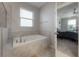 Bright bathroom featuring a soaking tub and open doorway to a bedroom with a ceiling fan and window at 9672 Ivory Dr, Ruskin, FL 33573