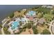 Aerial view of community pool, clubhouse, tennis courts, and recreational amenities near a lake at 9814 Quadrangle Ct, Sun City Center, FL 33573
