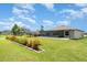 Manicured backyard featuring lush lawn, brick-lined garden beds, and a screened-in porch perfect for relaxation at 9814 Quadrangle Ct, Sun City Center, FL 33573