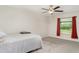 Bright bedroom features carpet flooring, a window with red curtains, and a ceiling fan at 9814 Quadrangle Ct, Sun City Center, FL 33573