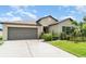 Inviting exterior of a home with a two-car garage, well-maintained lawn, and established landscaping at 9814 Quadrangle Ct, Sun City Center, FL 33573