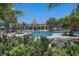 Community pool with ample lounge chairs and tables, surrounded by lush landscaping and palm trees at 9814 Quadrangle Ct, Sun City Center, FL 33573
