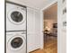 A stacked washer and dryer sits next to the living room with hardwood floors and a comfortable sofa at 3078 Eastland Blvd # 205, Clearwater, FL 33761