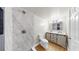 Bathroom with a modern vanity, wood floors, and walk-in shower with faux marble surround at 1005 45Th W St, Bradenton, FL 34209