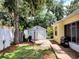 Charming backyard featuring a wooden walkway, storage shed, grill, mature trees, and partial fence at 1006 Tropical Dr, Bradenton, FL 34208
