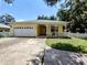 Charming yellow home featuring a welcoming front porch, two-car garage, and well-maintained front yard at 1006 Tropical E Dr, Bradenton, FL 34208