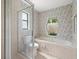 Bright bathroom featuring a tub and shower behind glass door, and unique window view at 1015 Hastings Ct, Lutz, FL 33548