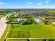 This aerial view captures a community with a playground, dog park, pool, basketball court, and surrounding residences at 10909 Kirkwall Port Dr, Wimauma, FL 33598
