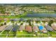 Aerial view displays houses bordering a serene lake with meticulous lawns and tree-lined streets at 10909 Kirkwall Port Dr, Wimauma, FL 33598