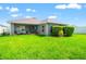 Well-manicured backyard featuring lush green grass and a cozy covered patio area at 10909 Kirkwall Port Dr, Wimauma, FL 33598