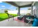 Relaxing covered patio featuring stylish outdoor furniture and a view of the well-maintained backyard at 10909 Kirkwall Port Dr, Wimauma, FL 33598