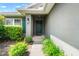 Close-up of the front door with decorative landscaping and a charming exterior lantern at 10909 Kirkwall Port Dr, Wimauma, FL 33598