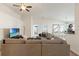 Spacious living room featuring a large sectional sofa, ceiling fan, and entertainment center at 10909 Kirkwall Port Dr, Wimauma, FL 33598