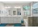 Bright bathroom with dual sinks, large mirror, soaking tub, and glass shower at 12004 Cinnamon Fern Dr, Riverview, FL 33579