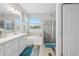 Bright bathroom with double vanity, large tub, and glass shower featuring stylish tile and wood-look floors at 12004 Cinnamon Fern Dr, Riverview, FL 33579