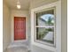 Inviting front entrance featuring a red door with decorative window and exterior lighting at 14047 Weddington Ter, Hudson, FL 34669