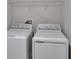 Bright laundry area featuring a white washer, dryer, and practical overhead storage shelf at 14047 Weddington Ter, Hudson, FL 34669
