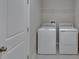 A clean laundry room features a side-by-side washer and dryer with wire shelving overhead at 14047 Weddington Ter, Hudson, FL 34669
