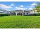 A spacious backyard with lush green grass, a screened lanai, and an extended patio at 15405 Woodstar Landing Ct, Lithia, FL 33547