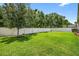 Well-manicured backyard with lush green lawn, mature trees, and a white fence for privacy at 17651 Bright Wheat Dr, Lithia, FL 33547