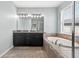 Bright bathroom featuring a soaking tub, granite countertops, and black cabinets at 17651 Bright Wheat Dr, Lithia, FL 33547