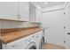 A spacious laundry room with custom cabinets, butcher block counters, washer and dryer hookups, and geometric backsplash at 2002 Carolina Ne Cir, St Petersburg, FL 33703