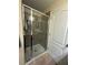 Bathroom shower with glass sliding door, shower head, and soap holder on a neutral tile wall at 2411 Willimette Dr, Wesley Chapel, FL 33543