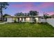 Charming single-story home with a lush green lawn and well-manicured landscaping at dusk at 2452 Bayshore Blvd, Dunedin, FL 34698